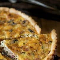 A cut slice of quiche being lifted showing the vegetables inside