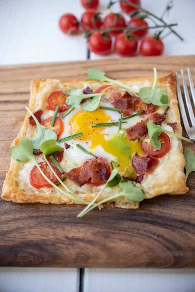 Bright yellow egg yolk running over the puff pastry and crispy bacon