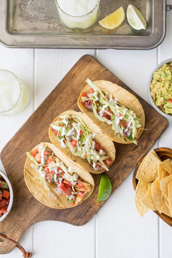 A feast of fish tacos, tortilla chips, salsa, guacamole and a lemon lime margarita