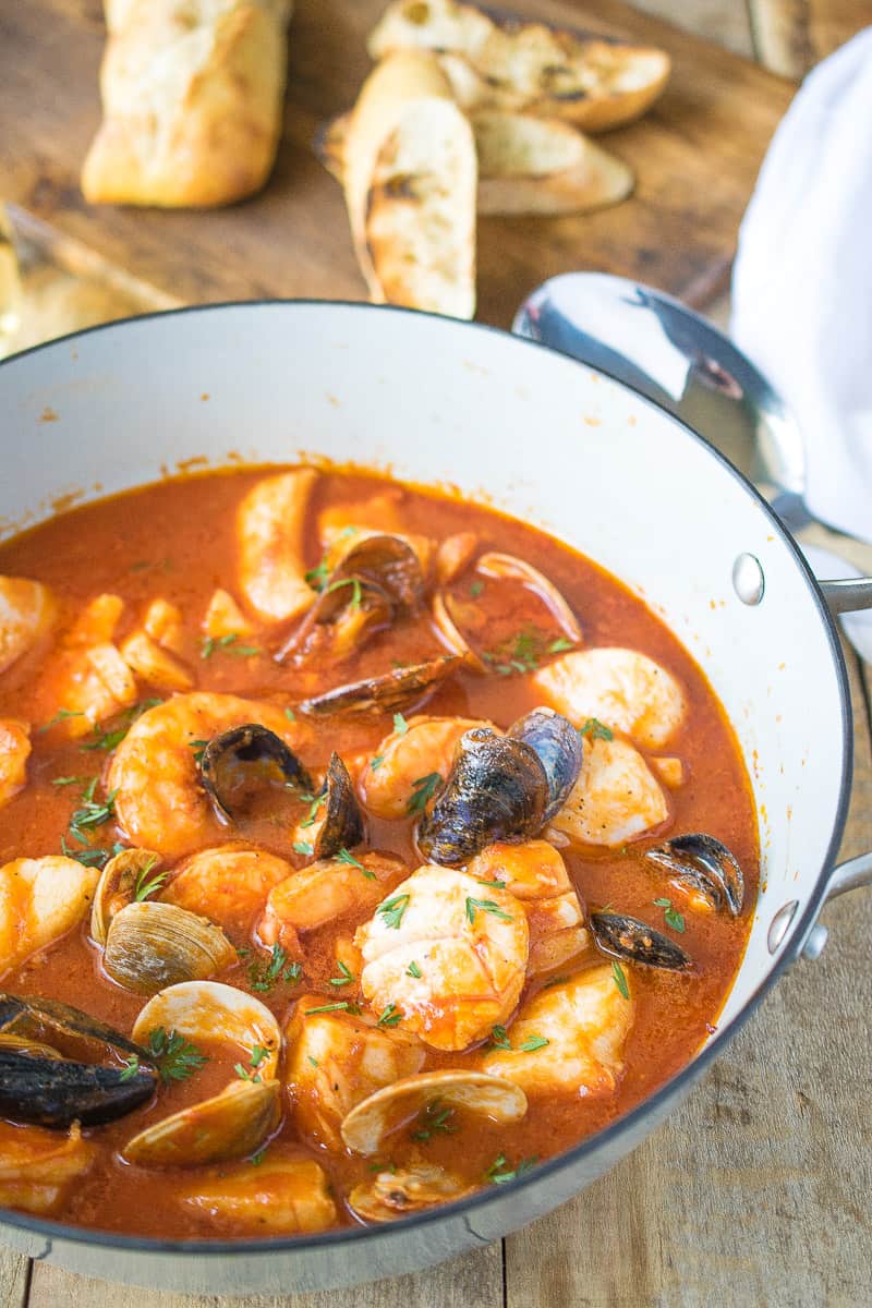 A large cast iron pan cooking the brodetto di pesce seafood