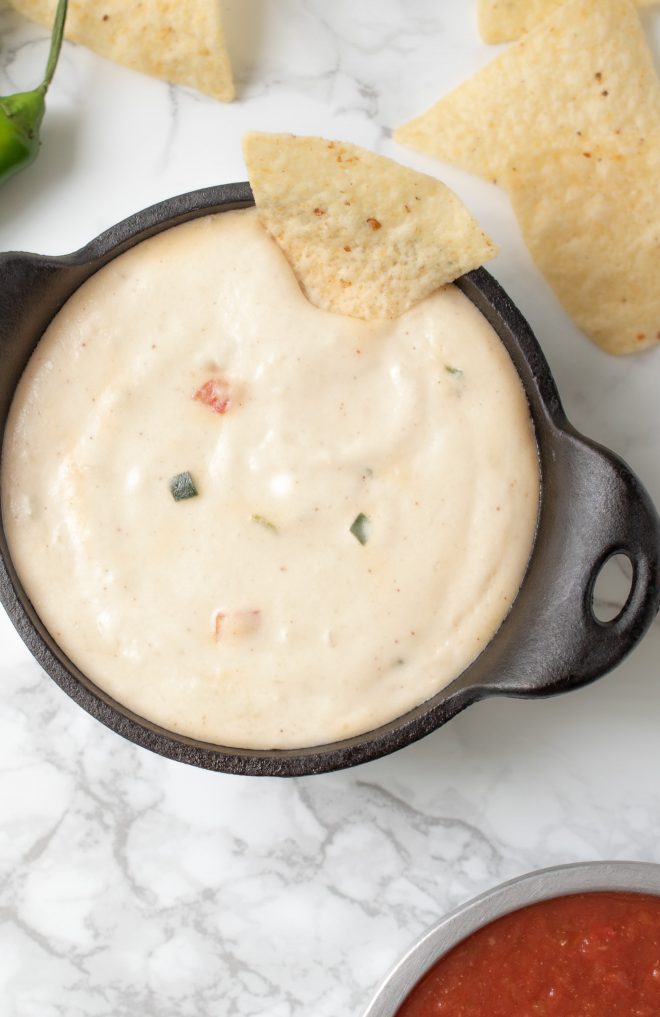 A closeup of queso blanco showing chunks of tomato and peppers