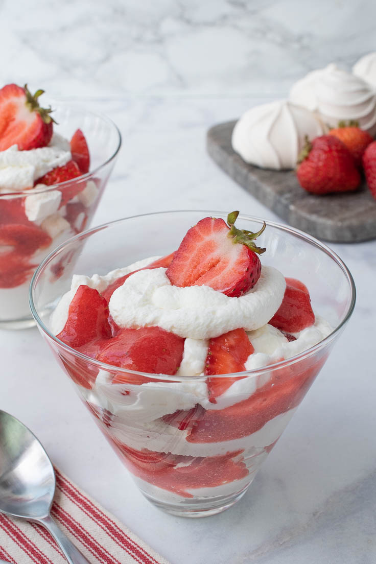 Layers of meringue, whipped cream and strawberries in a glass bowl