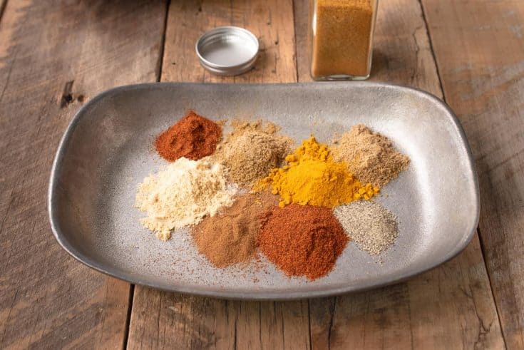 A grey bowl with small piles of different color spices
