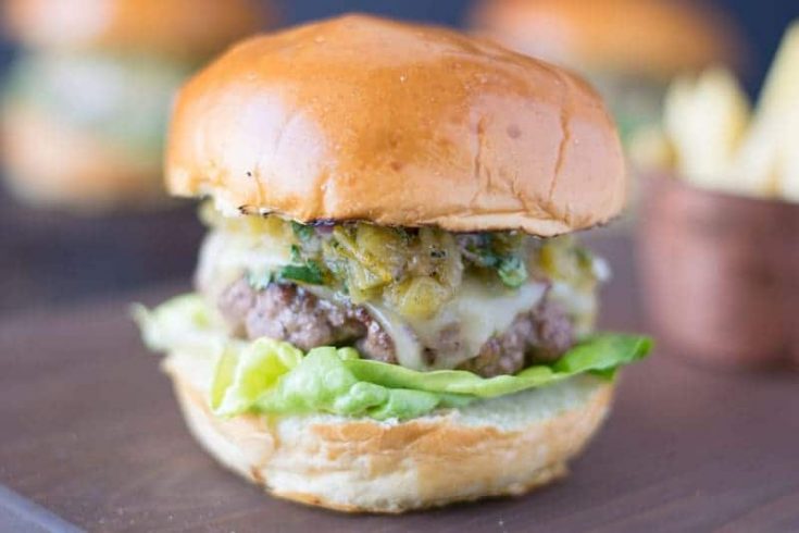 The burger from the side showing the melted cheese, chiles and lettuce