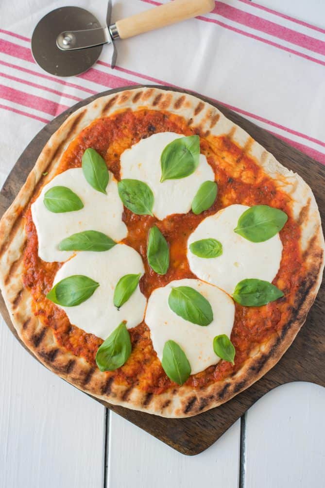 Uncut, viewed from overhead on a pizza board with a pizza cutter