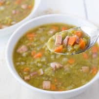 Chunks of ham, carrots split peas and potato on a spoon
