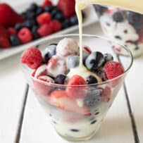 Hot English Custard being poured over colorful frozen berries.