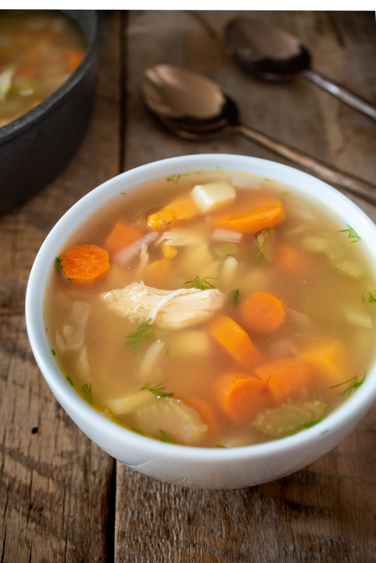 A bowl of chicken soup in a white bowl
