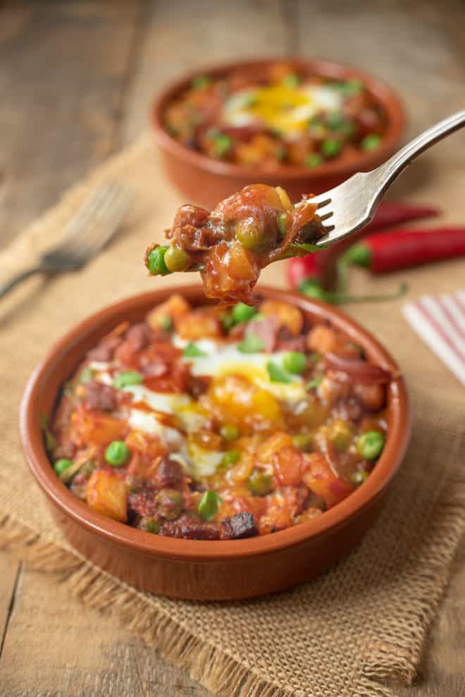 A fork full of potatoes, peas and chorizo Huevos a la Flamenca (Gypsy Eggs)