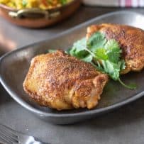 Chicken thighs on a grey serving platter with a side of rice