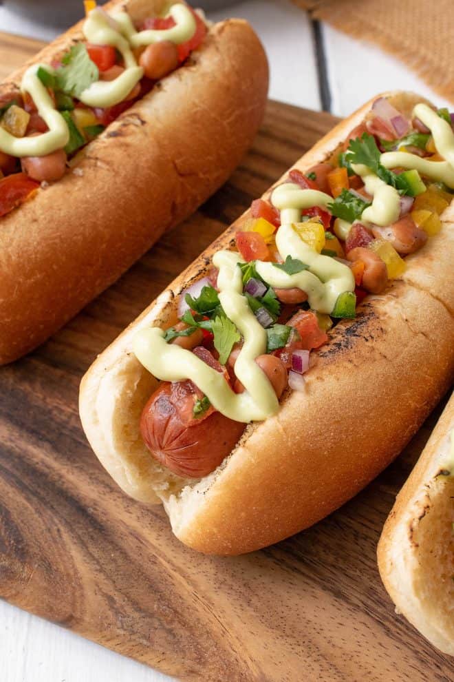 A closeup of the hot dog showing the pinto beans, salsa and avocado crema toppings