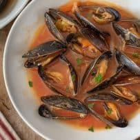 A closeup showing the mussels in their shells garnished with parsley