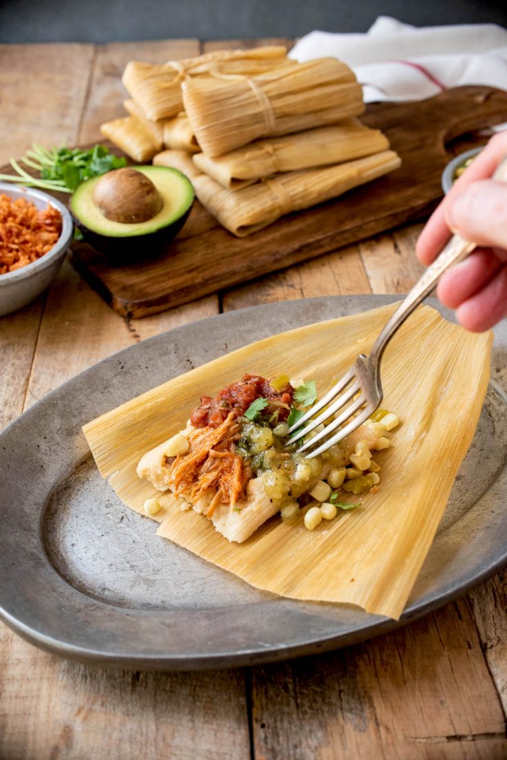 A tamale opened up with salsa and corn