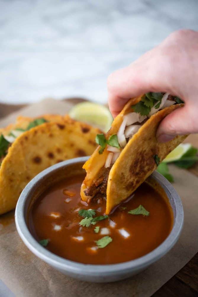 Dipping a quesabirria taco into consomme