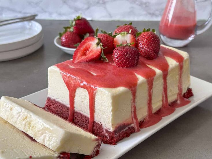 Red velvet cake topped with frozen semifreddo ice cream and strawberry sauce
