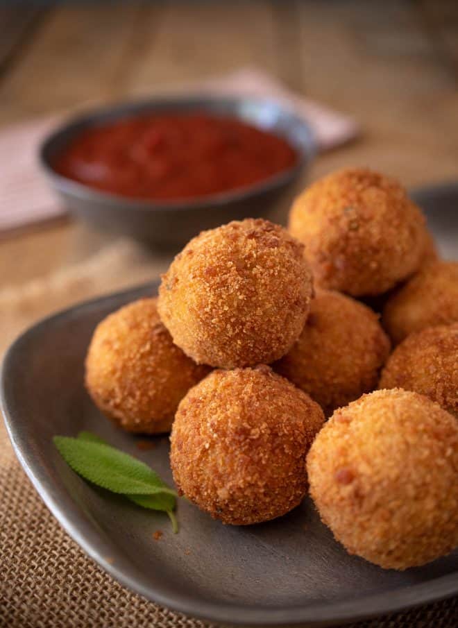 Fried rice balls stacked on a plate with fresh sage