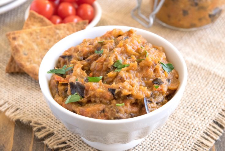 Roasted eggplant dip in a white bowl garnished with fresh parsley