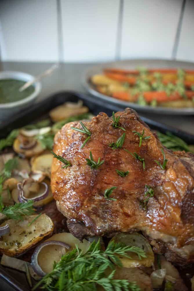 A boneless leg of lamb studded with fresh rosemary on a bed of potatoes and fennel