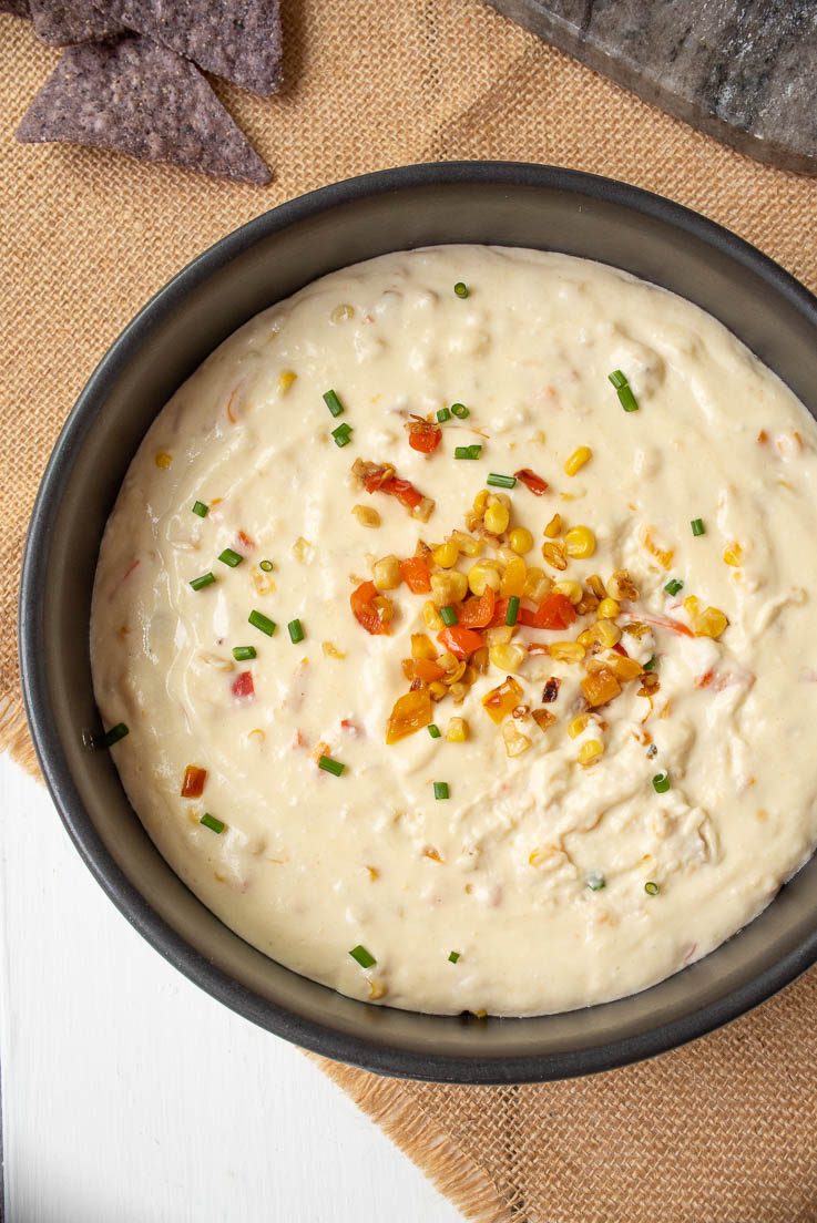The dip from overhead with the colorful red peppers yellow corn and green chives