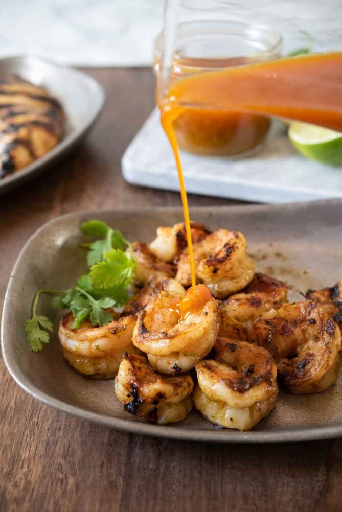 Pouring Sonoran Jalapeño Lime Sauce over grilled shrimp