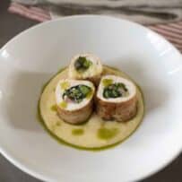 Sliced chicken roulade filled with vegetables served over polenta