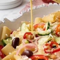 Pouring dressing over a colorful vegetables and pasta