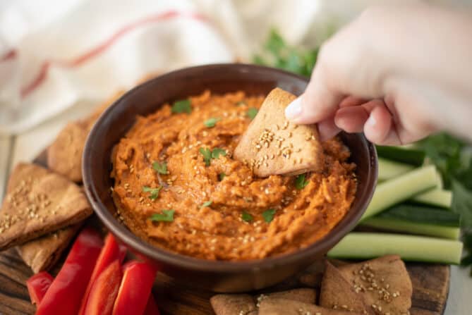 Using a pita chip to scoop up hummus
