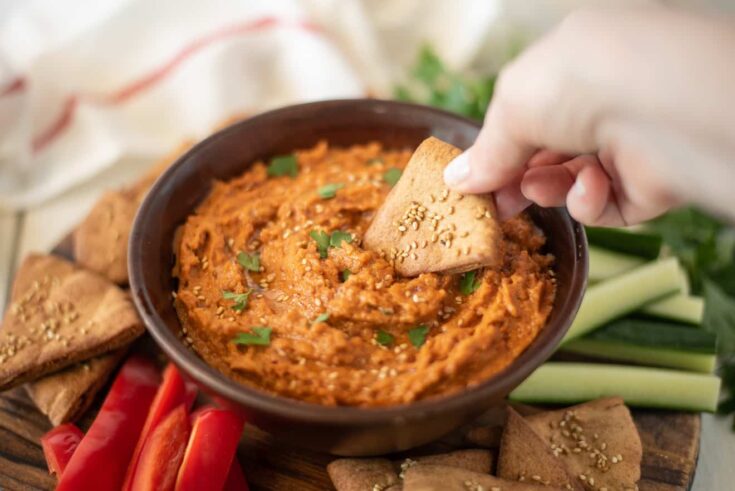 Using a pita chip to scoop up hummus