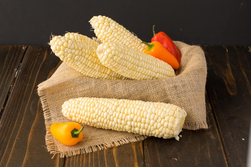Fresh corn cobs with colorful peppers,