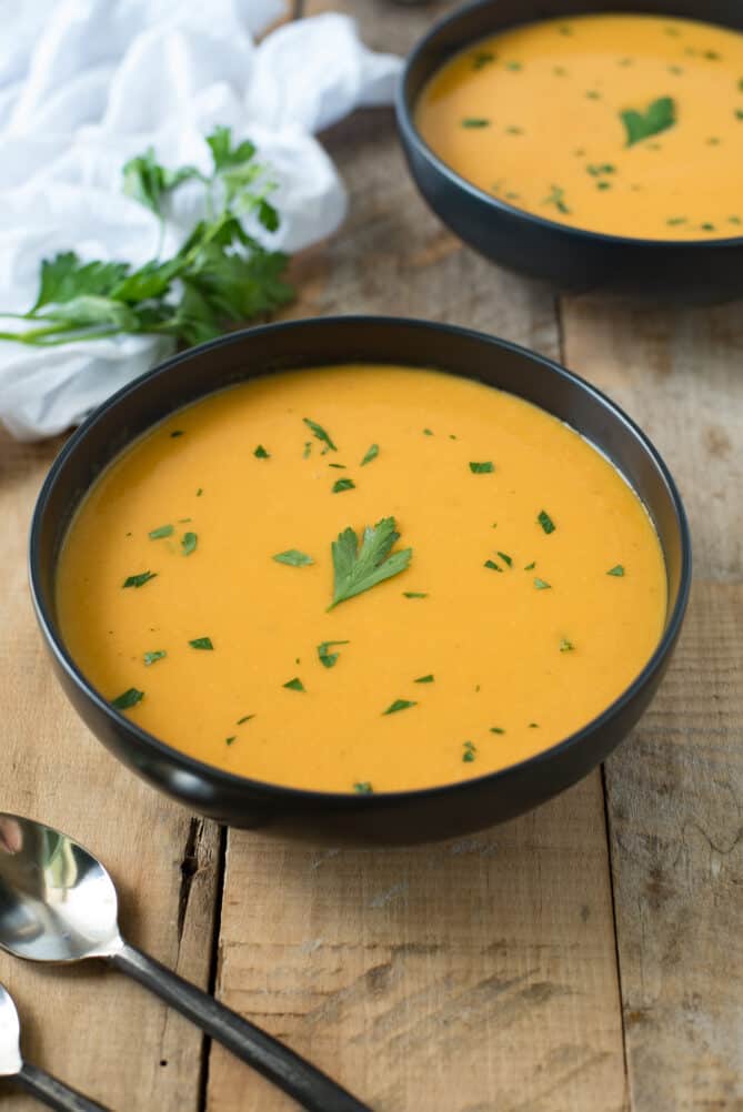 2 bowls of butternut squash soup with 2 spoons
