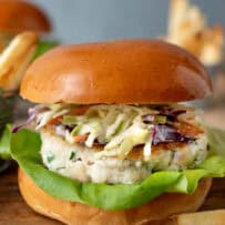 A tilapia fish burger and coleslaw on a brioche bun with fries