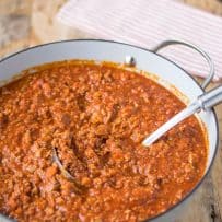 A serving spoon in a pan of Bolognese sauce