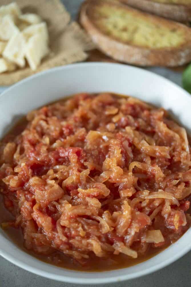 A closeup of onions and tomatoes that have been cooked until softened