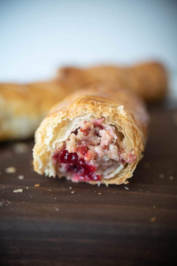 A view of the inside of the sausage rolls showing the bright cranberry and the flaky layers of pastry