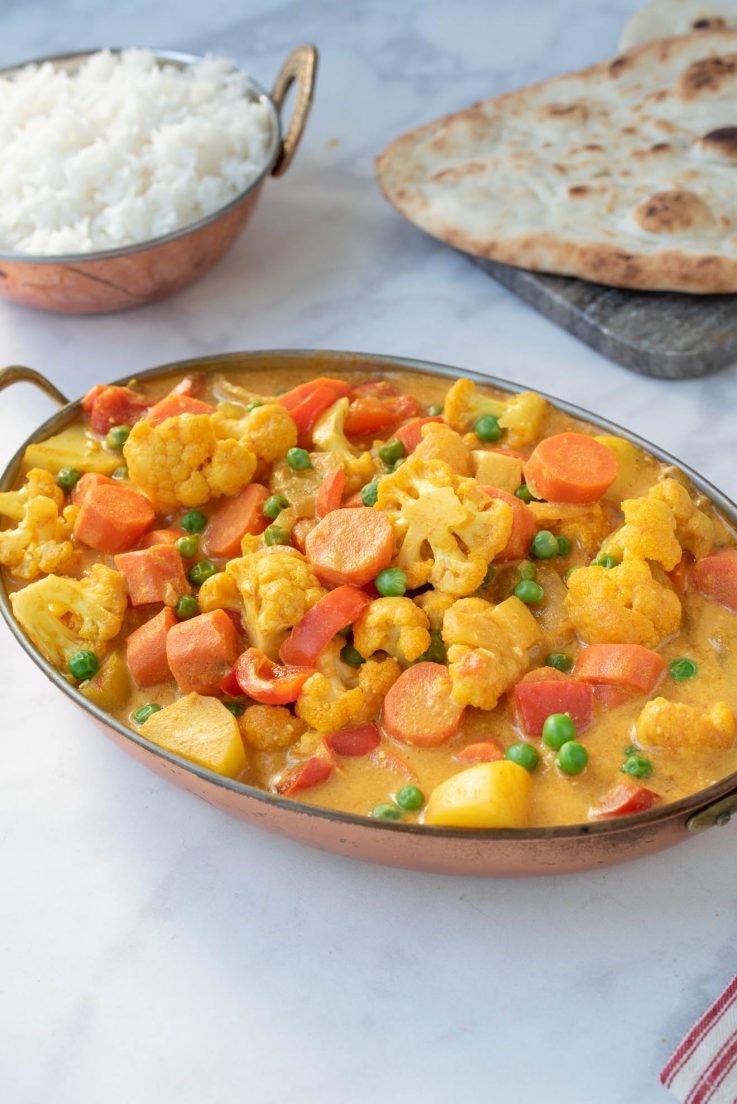 A colorful vegetable curry served in an oval dish