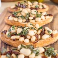 4 Warm Tuscan bean crostini lined up on a board